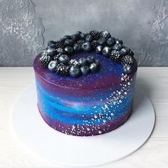 a blue and purple cake on a white plate with silver sprinkles around it