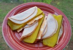 sliced pieces of fruit sitting on top of a red plate with grass in the background