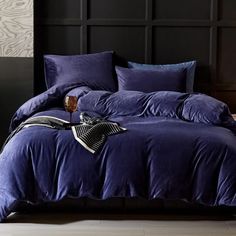 a bed with purple comforter and pillows on it in front of a black headboard