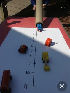 toy cars are lined up on a large white board with blue letters and numbers that spell out the word