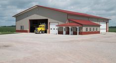 a yellow truck is parked in front of a large building with a red roof and two doors