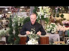 a man sitting at a table surrounded by flowers