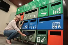 a woman leaning against a wall that has many different colored bins on it