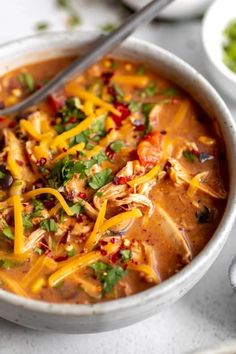 a white bowl filled with soup and topped with meat, cheese and cilantro