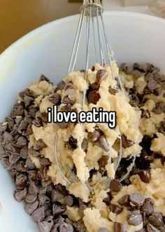 a white bowl filled with chocolate chip cookie dough and a whisk in it that says i love eating