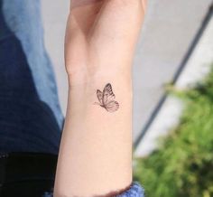 a woman's wrist with a small butterfly tattoo on the left side of her arm