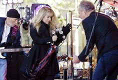 two men and a woman are playing music on the stage while one man is holding a guitar