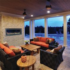 a living room filled with furniture and a fire place next to a swimming pool at night