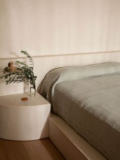 a bedroom with a bed, nightstand and plant