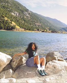 a woman sitting on rocks near the water