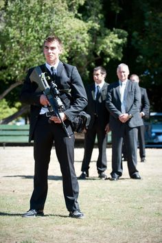 a man in a suit and tie holding a bagpipe while other men stand behind him