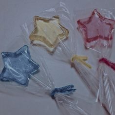 four star shaped lollipops wrapped in cellophane on a white surface