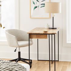 a desk with a lamp and chair in front of a window on a hard wood floor