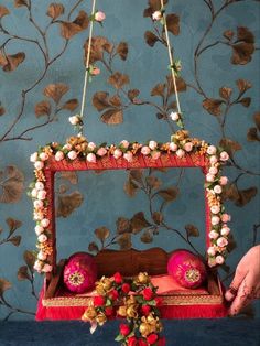 a bed with flowers on the headboard and hanging from it's sides in front of a blue wall