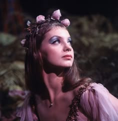 a woman with flowers in her hair is wearing a purple dress and posing for the camera