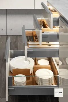 an open drawer in a kitchen filled with plates and bowls