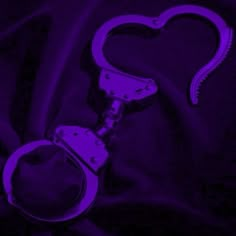 a pair of handcuffs sitting on top of a purple cloth next to a heart shaped object