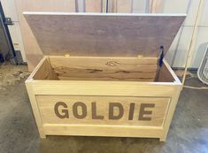 a large wooden box with the word goldie written on it in brown lettering, inside a garage