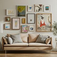 a living room filled with lots of framed pictures on the wall above a beige couch