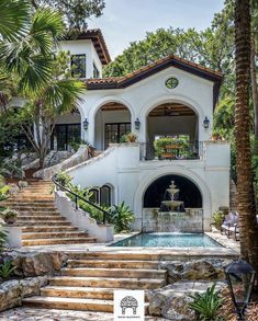 a large white house with stairs leading up to the front door and pool in the middle