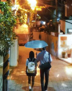 two people walking down the street with an umbrella