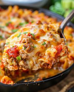 a spoon full of cheesy lasagna casserole with meat and vegetables