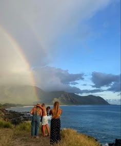 three women looking at a rainbow over the ocean