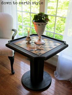 a small table with a potted plant on it in front of a large window