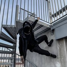 a man climbing up the side of a metal stair case with his hands in the air