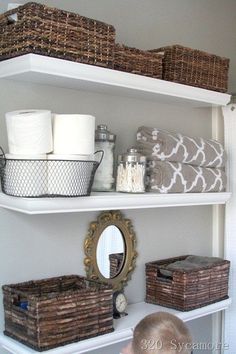 the shelves in this bathroom are organized with baskets and toilet paper