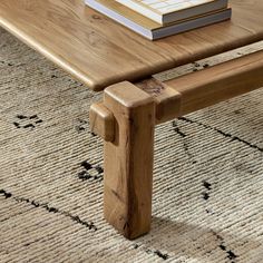 a wooden bench sitting on top of a rug next to a table with a book