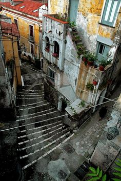 an old building with stairs leading up to the second floor and flowers growing in pots