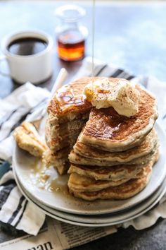 a stack of pancakes on a plate with syrup being drizzled over them