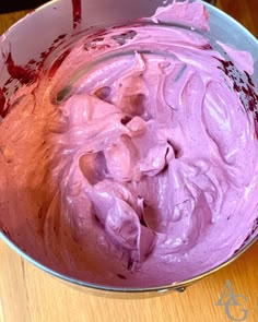 a metal bowl filled with purple food on top of a wooden table