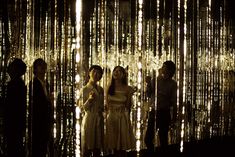 four people standing in front of a wall covered with lights