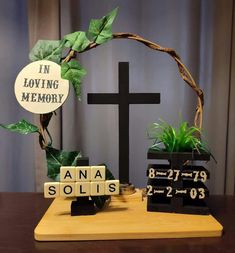 a cross, plant and blocks with words in loving memory on them sitting on a table