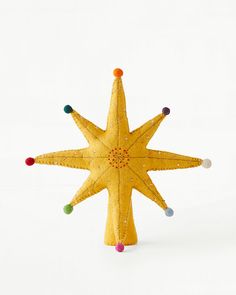 a yellow christmas ornament with multi - colored balls on it's star