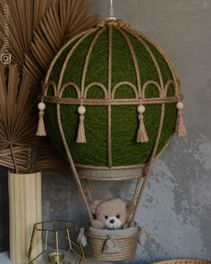 a teddy bear in a hot air balloon with tassels hanging from it's sides