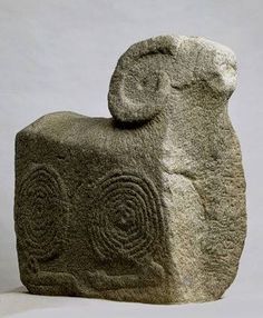 a stone sculpture with circles carved into it's face and on its back, in front of a white background