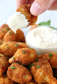 a person dipping sauce on top of some deep fried chicken nuggies with ranch dressing