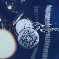 a harry potter pocket watch sitting on top of a blanket next to a lit candle