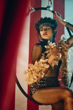 a woman is dressed up as a circus dancer with feathers on her head and holding a hoop