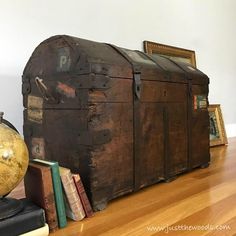 an old trunk sitting on top of a wooden floor next to books and a globe