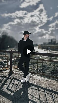 a man standing on top of a bridge next to snow covered mountains