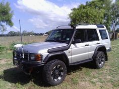 a white suv parked on top of a grass covered field