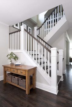 there is a table with baskets under the bannister on the floor next to the stairs