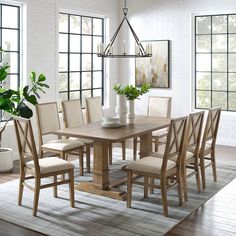 a dining room table and chairs in front of large windows with potted plants on top