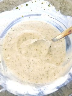 a glass bowl filled with white sauce and a wooden spoon