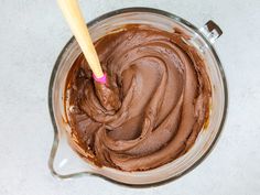 a bowl filled with chocolate frosting and a wooden spoon