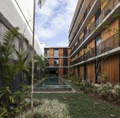 an apartment building with a pool surrounded by plants and trees in the foreground is a courtyard